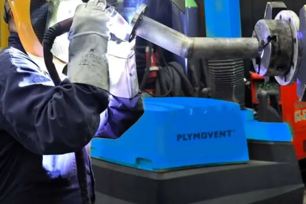 A man welding with a protective mask on and by his side there is a yellow Remove The Fume Fume Extractor who's extraction arm is sucking all the harmful fumes away.