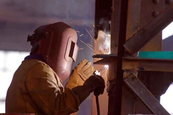 A man welding with a brown color protective mask on.