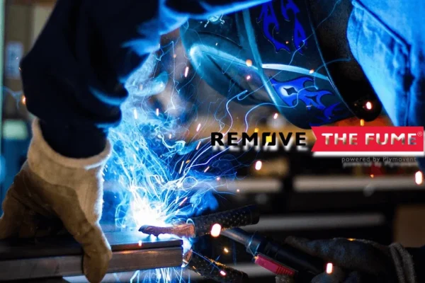 A close up shot of a man welding with a welding mas on while harmful fumes are being generated.
