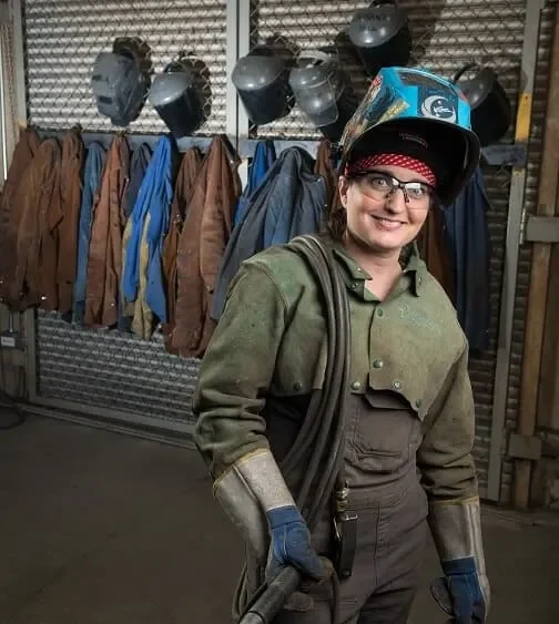 A female welder names Nicole LeClair, is wearing a protective eyewear, gloves and jacket for welding