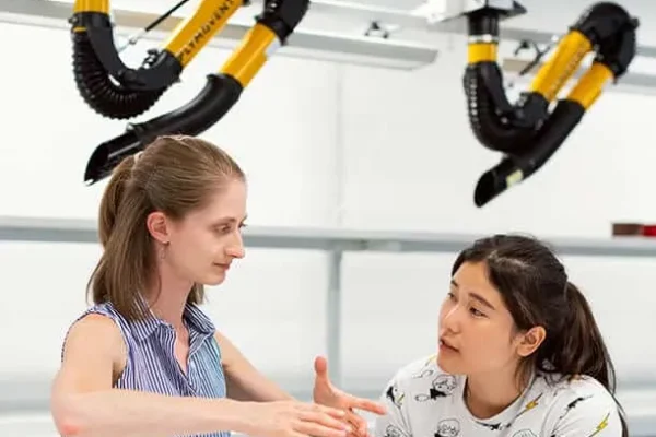 2 women having a discussion with 2 Plymovent arms in background