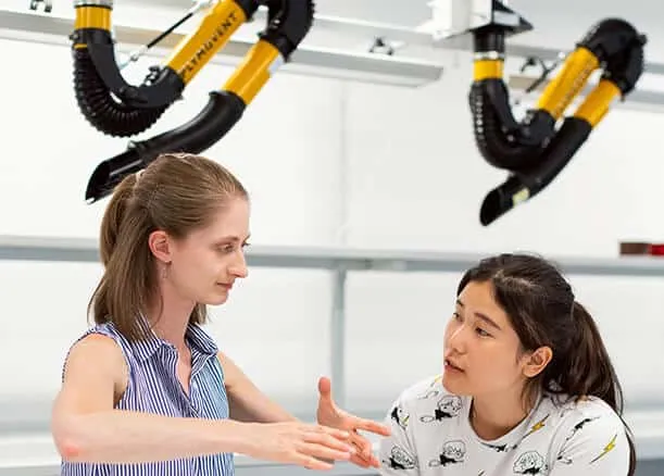 2 women having a discussion with 2 Plymovent arms in background