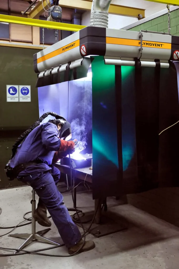 A man welding inside Plymovent's FlexHood Extraction hoods which is inhaling all the harmful welding fumes away.