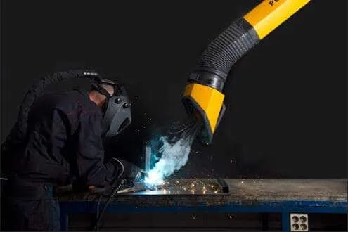 A man welding with a protective mask on a while yellow Remove The Fume fume extractor arm is inhaling all the harmful fume away.